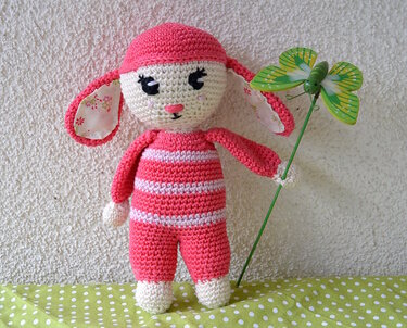 Gehäkeltes rosa-weiß gestreiftes Amigurumi-Häschen mit stoffgefütterten Ohren und grüner Schmetterlingsdeko
