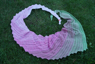 Gestricktes Dreieckstuch mit rosa‑grünem Farbverlauf und Zackenrand auf Gras