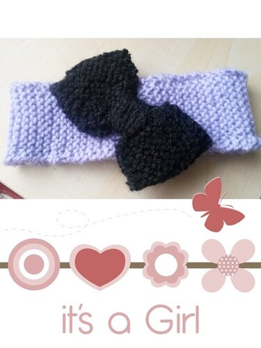 Gestricktes fliederfarbenes Baby-Stirnband mit großer schwarzer Schleife und 'it's a Girl'-Schriftzug