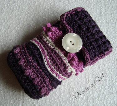 Gehäkeltes Utensilo in Lila- und Violetttönen mit strukturierten Mustern und weißlichem Knopf.