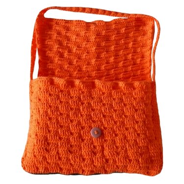 Orange gehäkelte Umhängetasche mit strukturiertem Muster und rosafarbenem Knopf auf weißem Hintergrund