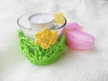 Glaswindlicht mit grünem Häkelbezug und gelben Häkelblüten, rosa Tulpe daneben