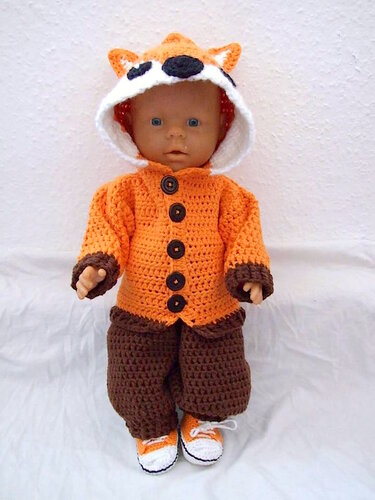 Puppe mit orange gehäkelter Fuchsjacke mit Kapuze, brauner Häkelhose und orange-weißen Häkel-Schuhen.