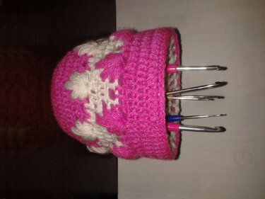 Pinkes gehäkeltes Utensilo mit weißen Schneeflocken, gefüllt mit Häkelnadeln