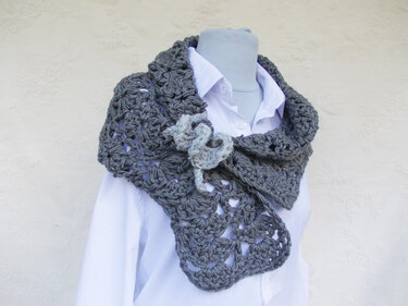 Mannequin trägt graues gehäkeltes Dreieckstuch mit Lochmuster und kleiner Blüten-Applikation über weißem Hemd