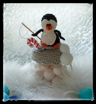 Niedlicher gehäkelter Pinguin als Aufsatz auf einem Glasgefäß mit Zuckerstange, Angel und Pompons.