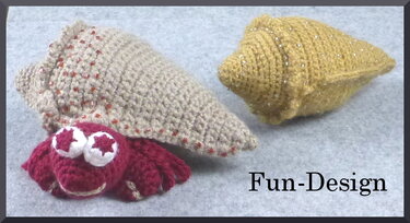 Rote gehäkelte Amigurumi-Krabbe neben einer beigen Muschel mit Perlen und einer gelben Muschel mit Glitzer auf hellem Untergrund.