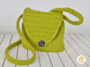 Gehäkelte lindgrüne Umhängetasche mit Klappe und dunklem Knopf