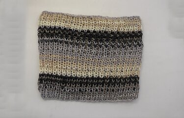 Gefalteter gestrickter Loop-Schal mit breiten Streifen in Beige, Grau und Schwarz auf hellem Hintergrund