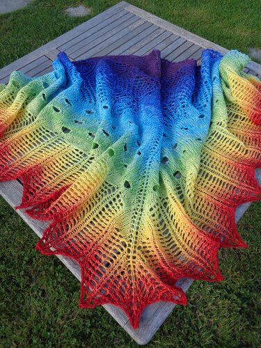 Gestricktes Dreieckstuch in Regenbogenverlauf mit Lochmuster und gezacktem Rand auf Holztisch