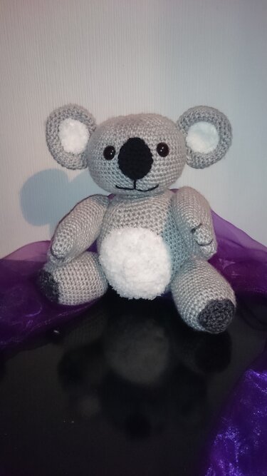 Gehäkelter grauer Koala-Amigurumi mit weißem Bauch und dunkler Nase