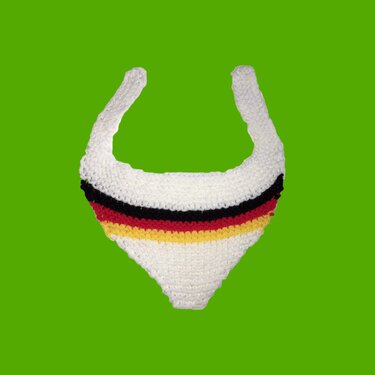 Weißes, gestricktes Baby-Halstuch mit schwarzen, roten und goldfarbenen Streifen vor grünem Hintergrund