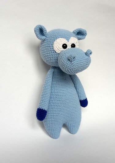 Gehäkeltes Nilpferd in Hellblau mit dunklen Pfoten und weißen Augen, frontseitlich