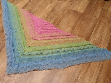 Gestricktes Dreieckstuch mit Pastell-Farbverlauf (Blau, Grün, Gelb, Pink) auf Holzboden