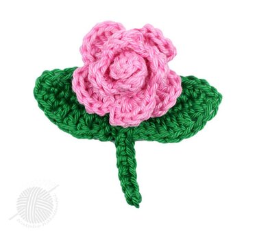 Aufwendig gehäkelte rosa Rose mit grünen Blättern und kurzem Stiel auf weißem Hintergrund