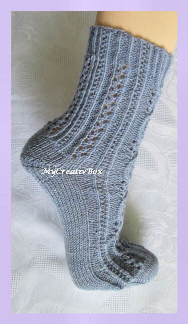 Gestrickte graublaue Socke mit Rippen- und Ajourmuster, Seitenansicht mit Ferse