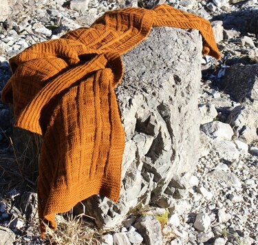 Textur und Muster eines rostorangenen Strickschals auf Fels