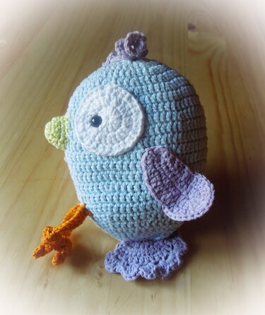 Nahaufnahme eines hellblauen gehäkelten Amigurumi-Vogels mit Fokus auf Körperform, Flügel und Fußdetails