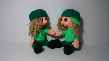 Zwei gehäkelte Amigurumi-Puppen in grüner Kleidung, die Händchen halten