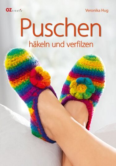 Bunte, gehäkelte und verfilzte Regenbogen-Puschen mit Blumenapplikationen an den Füßen.