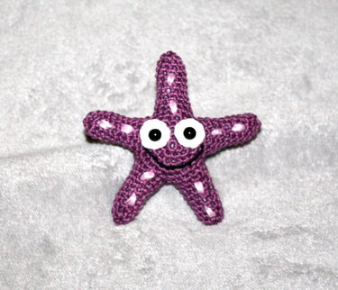 Fröhlich lächelnder lila Seestern aus Häkelgarn mit weißen Details