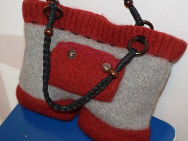 Grau-rote gestrickfilzte Tasche mit aufgesetzter Fronttasche und geflochtenem schwarzem Trageriemen mit Holzperlen