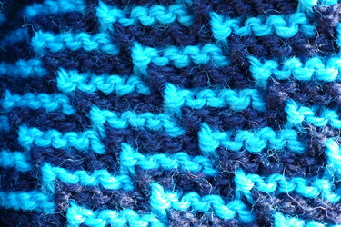 Nahaufnahme eines zweifarbigen Strickmusters in zwei Blautönen mit strukturierter Maschenordnung