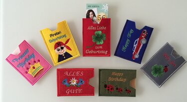 Sieben bestickte Filz-Kartenhüllen mit Einschubfach und Motiven wie Pirat, Kleeblatt, Krone und Edelweiß