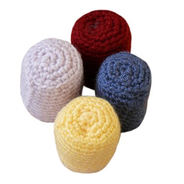 Vier gehäkelte Zylinder in Dunkelrot, Dunkelblau, Gelb und Flieder auf weißem Hintergrund