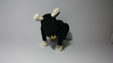 Gehäkelter schwarzer Stier mit cremefarbenen Hörnern und Hufen und gelbem Nasenring