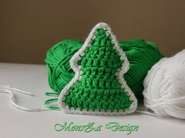 Gehäkelter grüner Tannenbaum mit weißer Umrandung vor grünen und weißen Garnknäueln