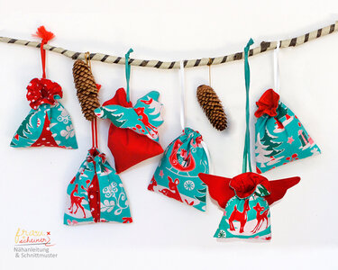 Genähte Weihnachtsbeutel in Rot und Türkis mit Rentier- und Tannenbaum-Motiven an einer Kordel