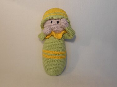 Amigurumi-Puppe mit ovalem Körper, angesetzten Armen, Mütze und gelbem Rüschenkragen