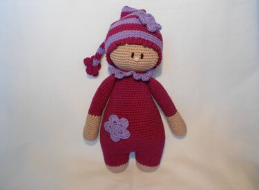 Gehäkelte Amigurumi-Puppe in Pink und Lila mit gestreifter Zipfelmütze und Blütenverzierung