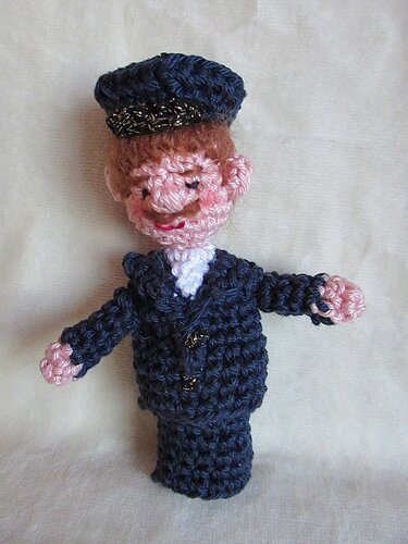Gehäkelte Amigurumi-Fingerpuppe eines Mannes in dunkler Uniform mit Schirmmütze
