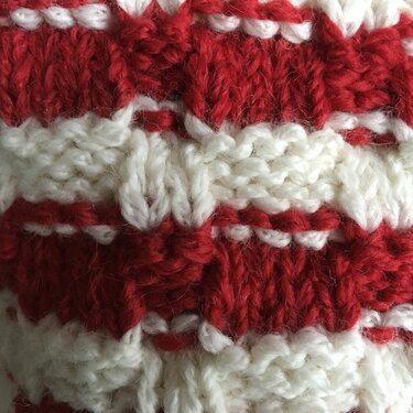 Nahaufnahme gestrickter Maschen mit roten und weißen Streifen und sichtbarer Reliefstruktur