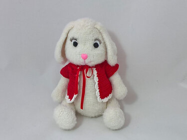 Weißer gehäkelter Amigurumi-Hase mit roter Jacke und rosa Nase