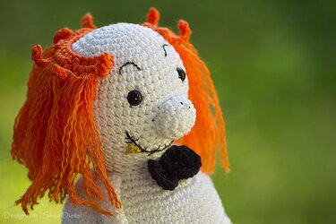 Gehäkelter weißer Geist mit orangefarbener Mähne und schwarzer Schleife