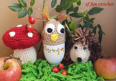 Eulen-Eierwärmer auf Eierbecher, gehäkelter Fliegenpilz und Igel zwischen Äpfeln und Hagebutten