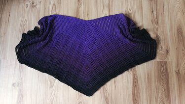Symmetrisches gehäkeltes Dreieckstuch in Violett und Schwarz mit regelmäßigen Reihen auf Holzboden
