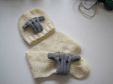 Gestrickte cremefarbene Babymütze und passender Schal mit grauer Schaf-Applikation und Knopfaugen