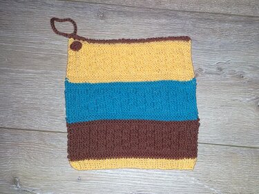 Quadratischer gestrickter Topflappen mit horizontalen Streifen in Gelb, Türkis und Braun und Aufhängeschlaufe oben links.