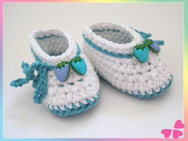 Weiß-türkise gehäkelte Babyschuhe mit Erdbeerknöpfen und Schleife