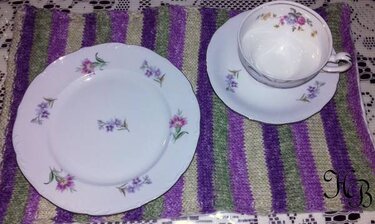 Gestrickter gestreifter Tischläufer in Lila, Grün und Beige mit Porzellanteller und Teetasse