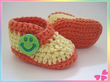 Gehäkelte Babyschuhe in Orange und Gelb mit grünem Smiley-Knopf