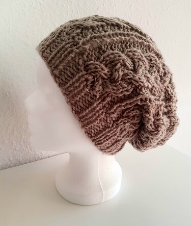 Gestrickte braune Beanie mit Zopfmuster auf weißem Modellkopf