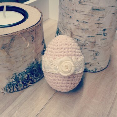 Rosa gehäkeltes Osterei mit weißem Spitzenband und Stoffrosen-Applikation vor Birkenholz-Deko