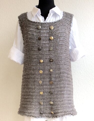 Gehäkelte taupefarbene ärmellose Tunika mit zweireihiger Knopfleiste auf Mannequin über weißer Bluse