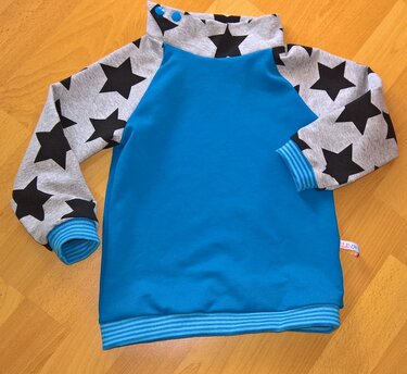 Türkisblauer Kinderpullover mit grauen Sternenärmeln, hohem Kragen und gestreiften Bündchen