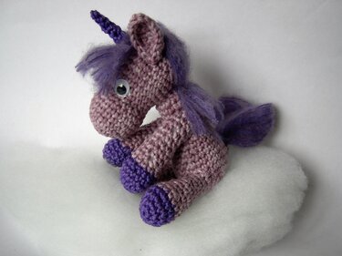 Gehäkeltes Amigurumi-Einhorn in lila mit violetter Mähne auf weißem Untergrund